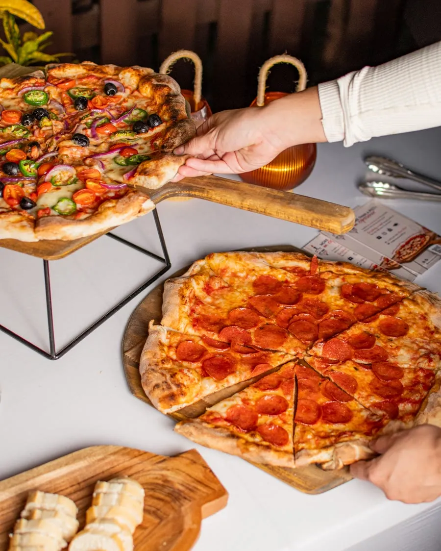 Fresh pizzas plated on wooden boards at a My Way Pizza catering setup