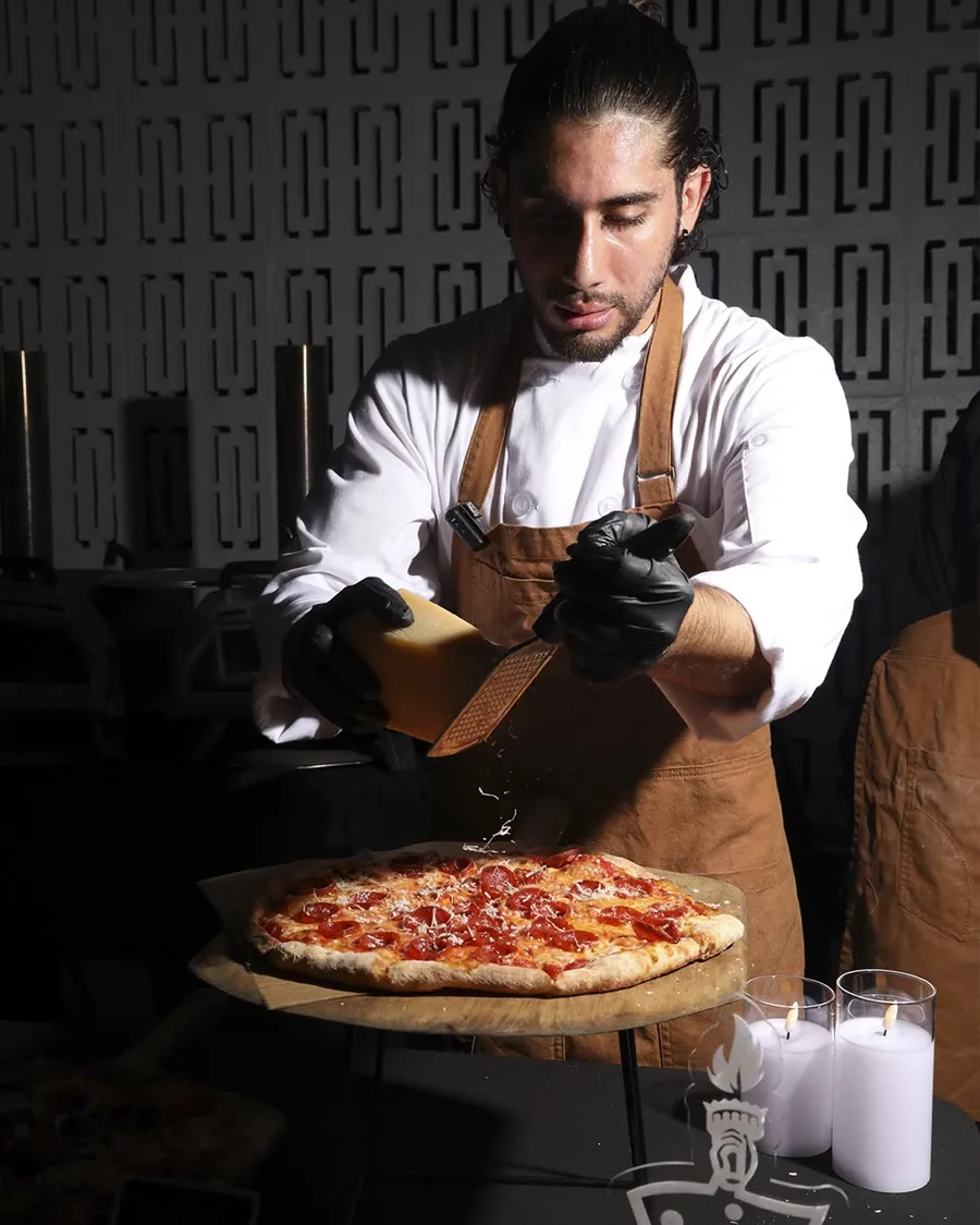 A My Way chef plating pizza at the live station during service