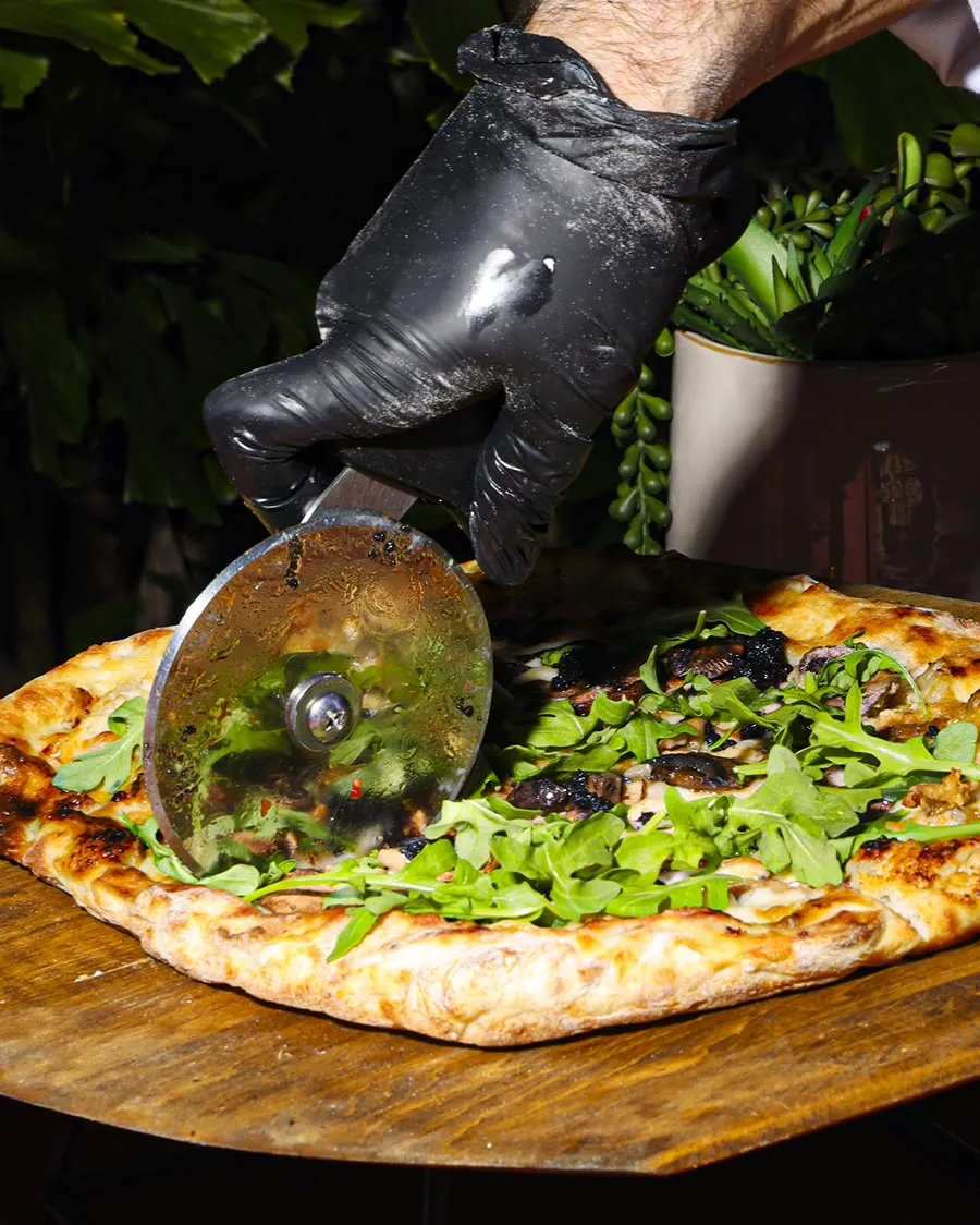 A pizza being cut into slices at the station during a celebration