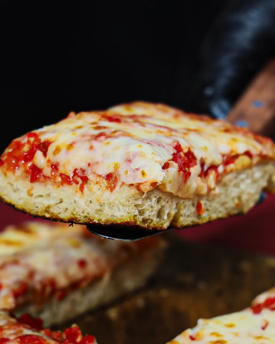 A thick, naturally leavened NY-style slice lifted from the tray