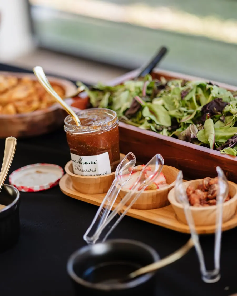 A fresh salad and dips station set on black linen at a wedding